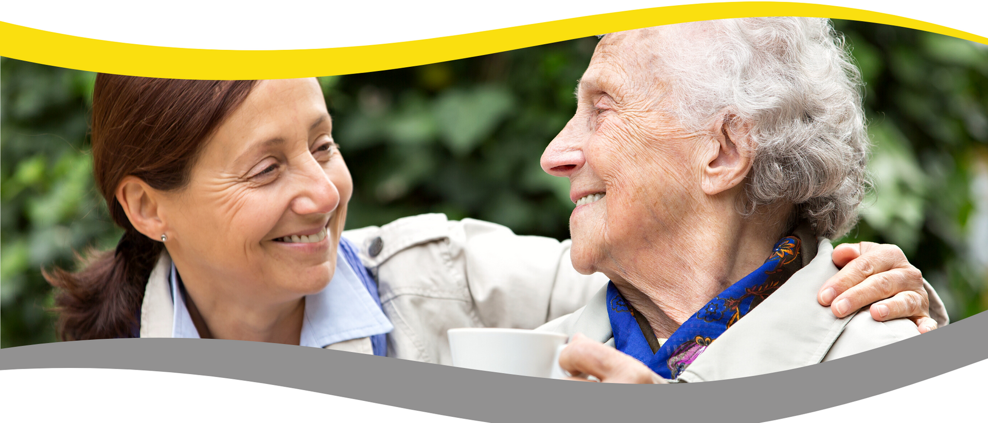 A woman is hugging an older woman while holding a cup of coffee.