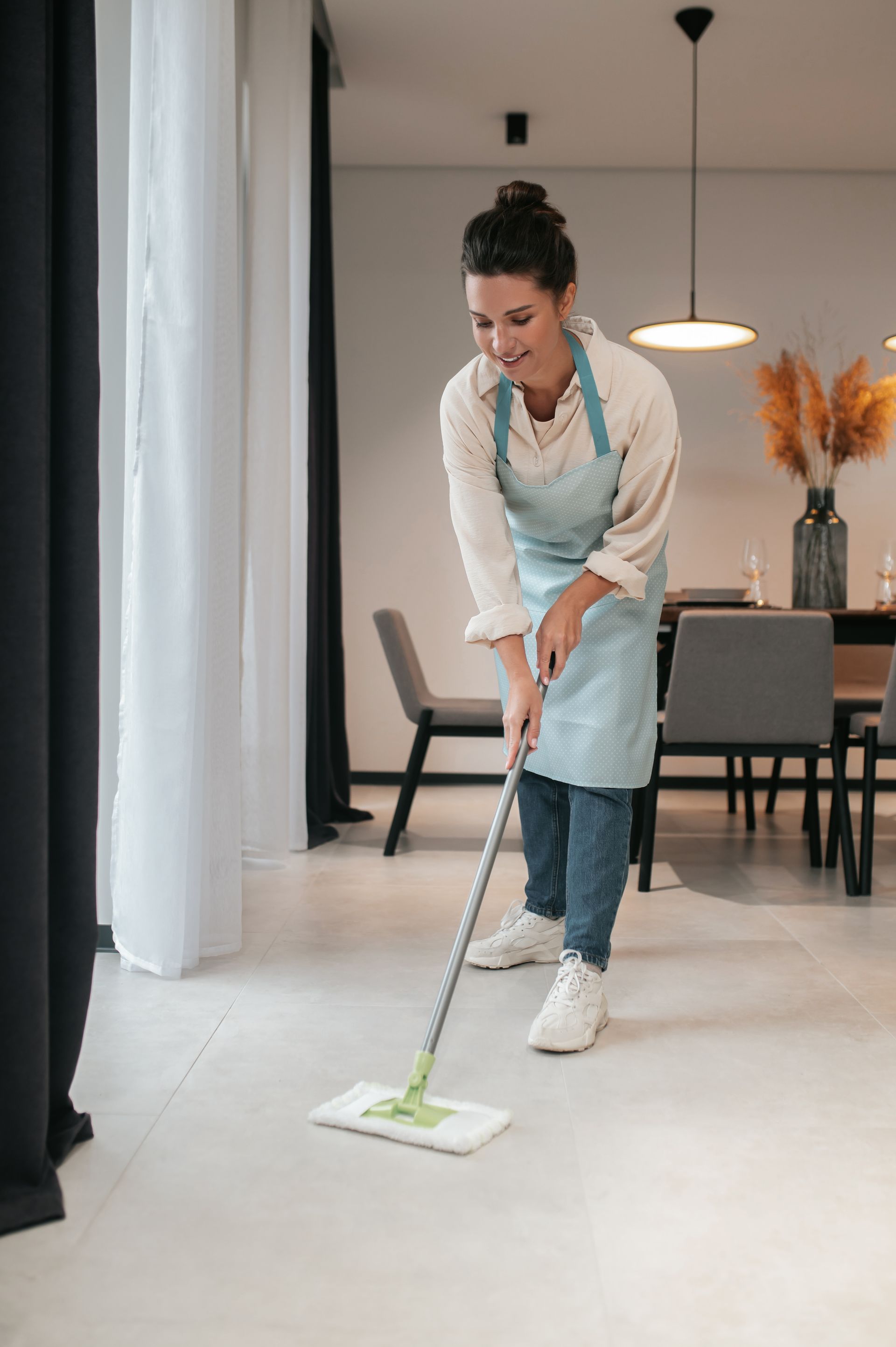 A woman is cleaning the floor with a mop in a living room.