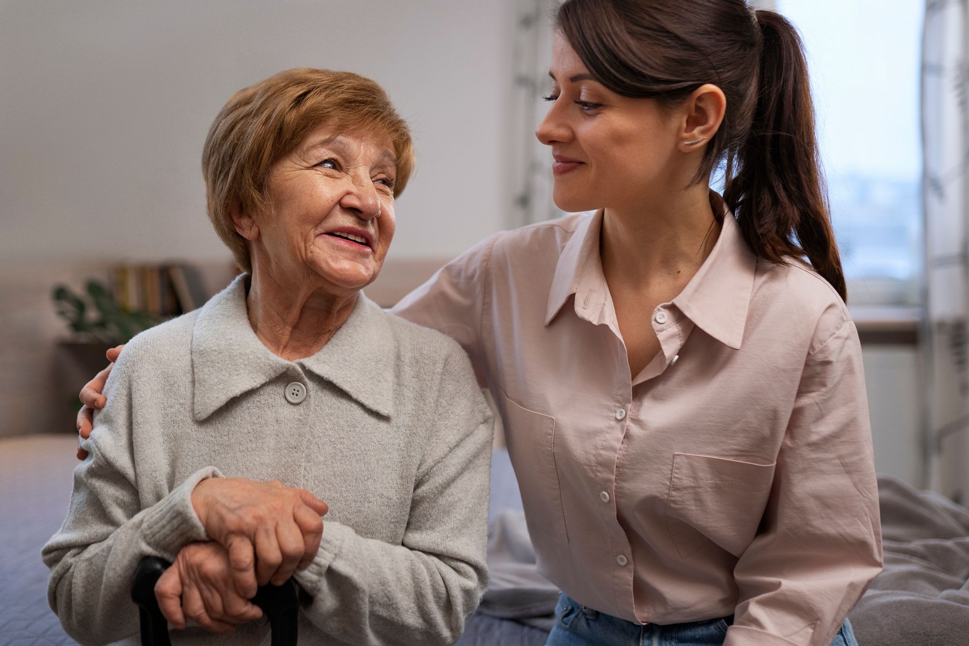 A young woman is talking to an older woman in a wheelchair.