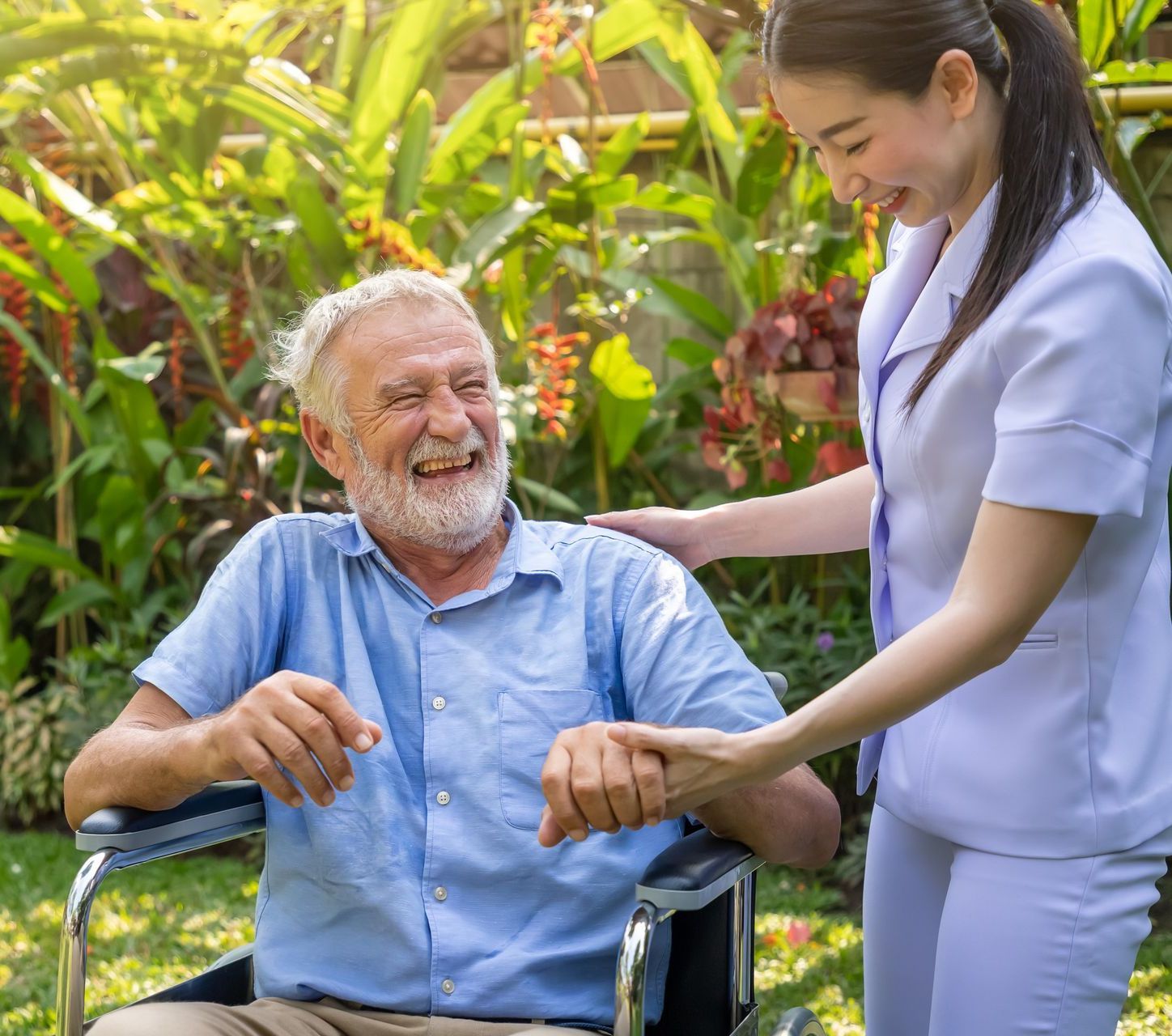 An elderly man in a wheelchair is being helped by a nurse.