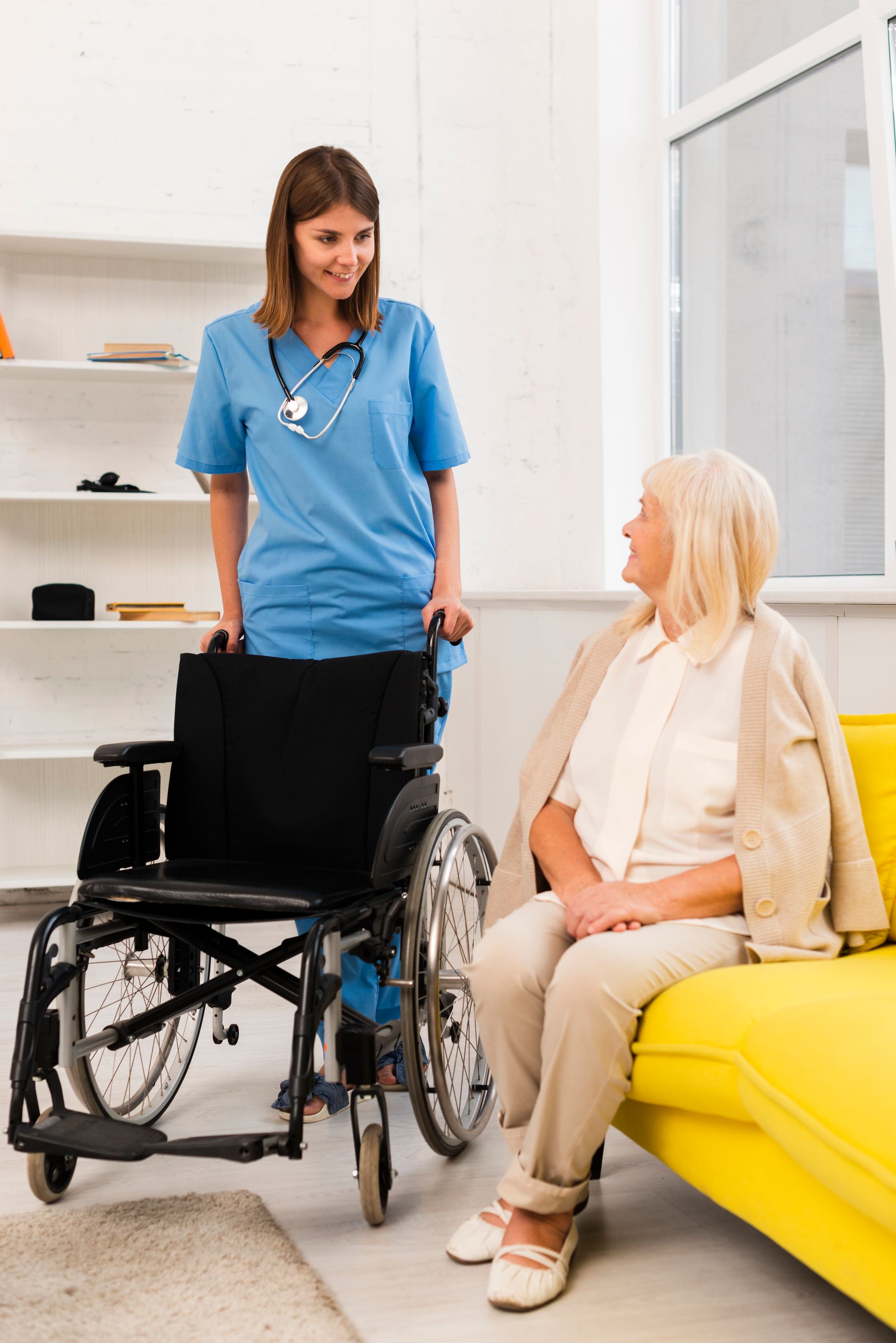 A nurse is talking to an elderly woman in a wheelchair.