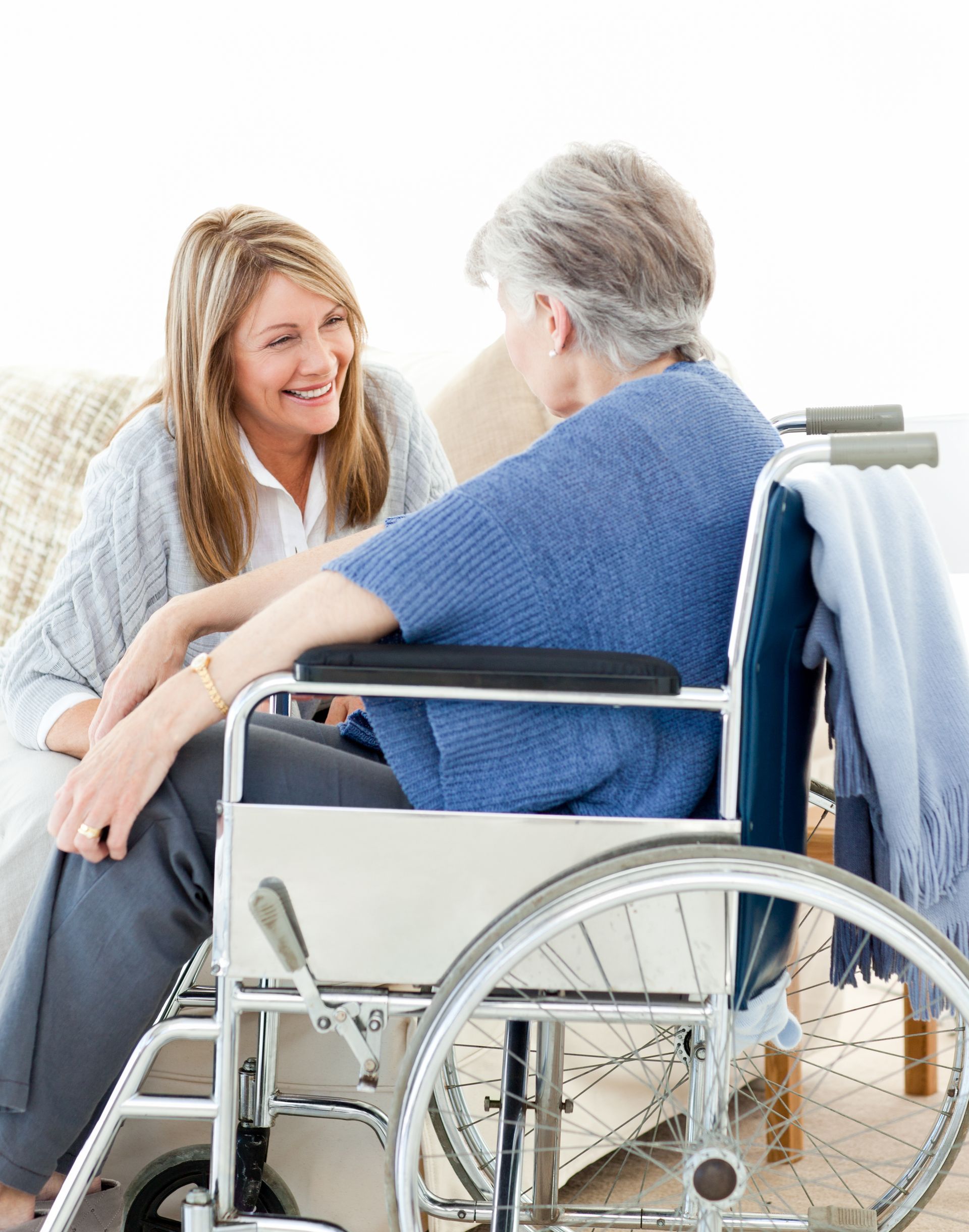 A woman is talking to an elderly woman in a wheelchair.