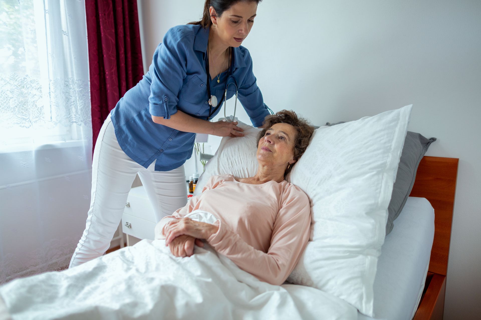 Nurse attending to a person lying in bed; examining them.
