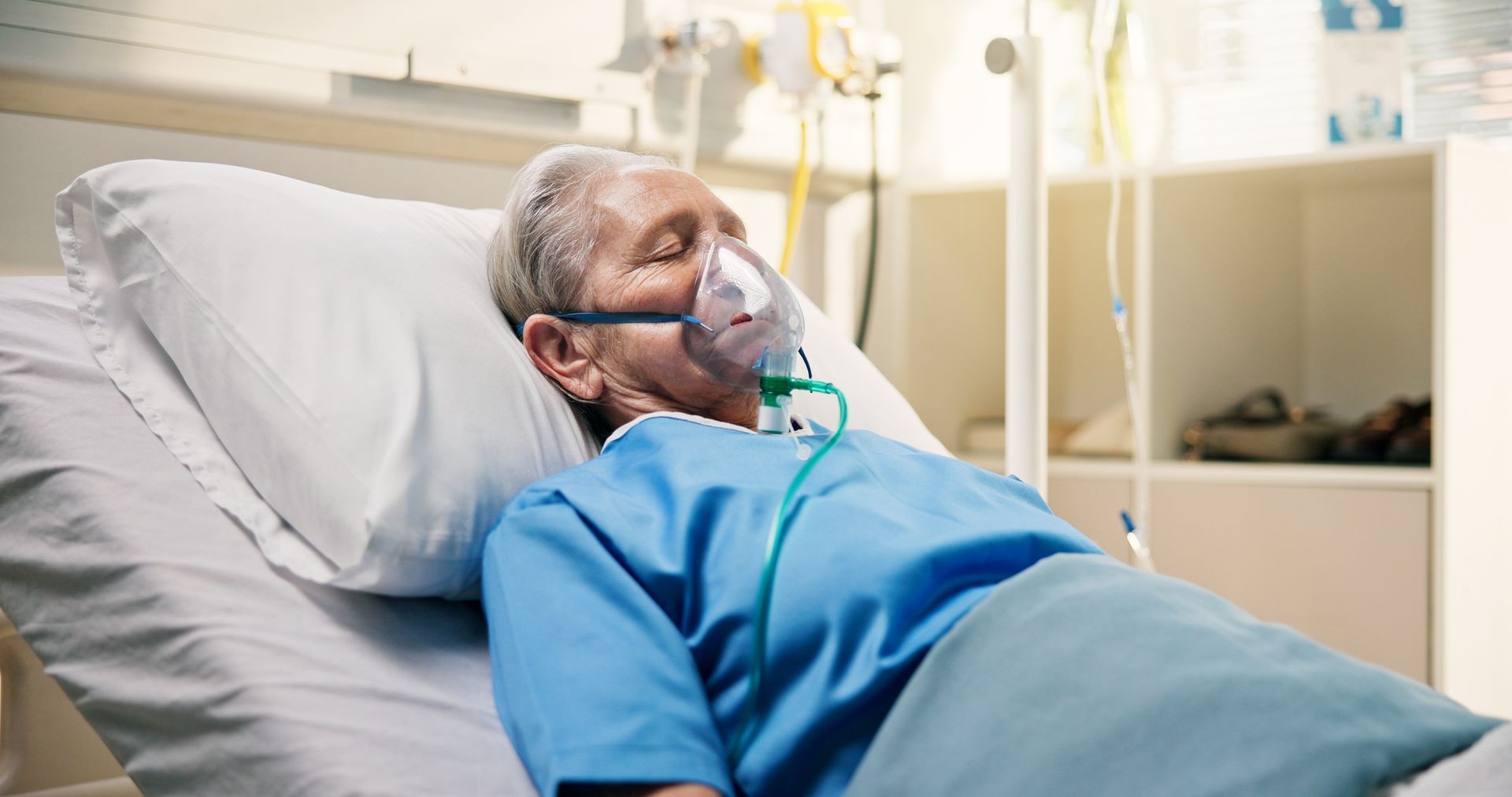 Person in hospital bed wearing oxygen mask.