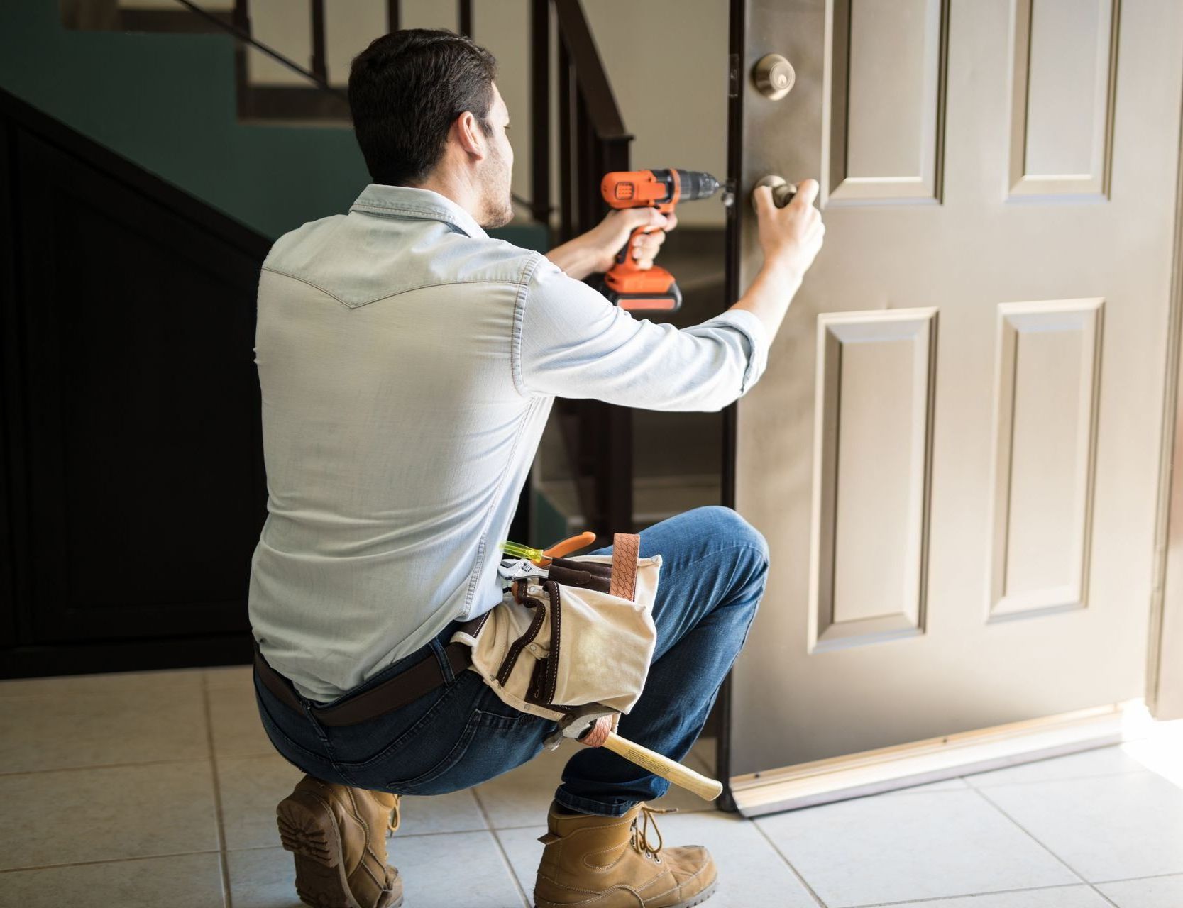 A man is fixing a door with a drill.