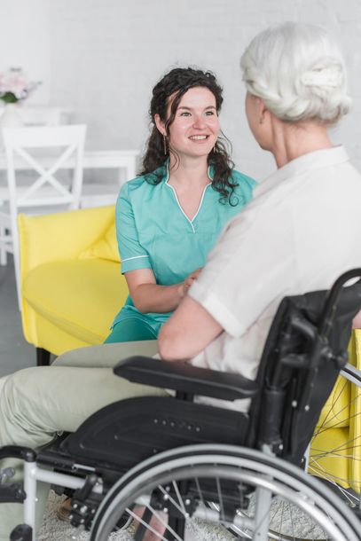 A nurse is talking to an elderly woman in a wheelchair.