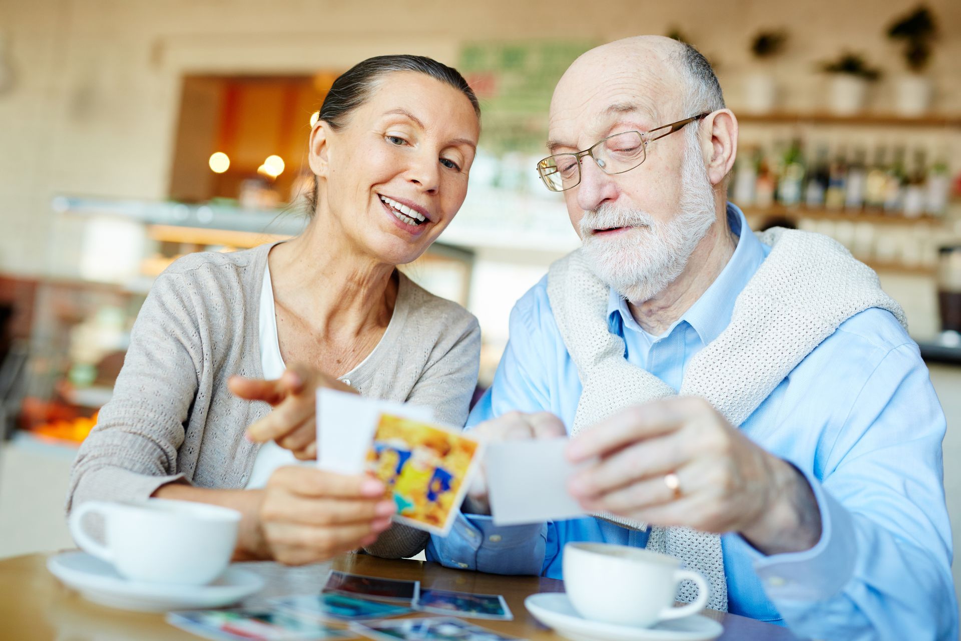 A man and a woman are sitting at a table looking at cards.