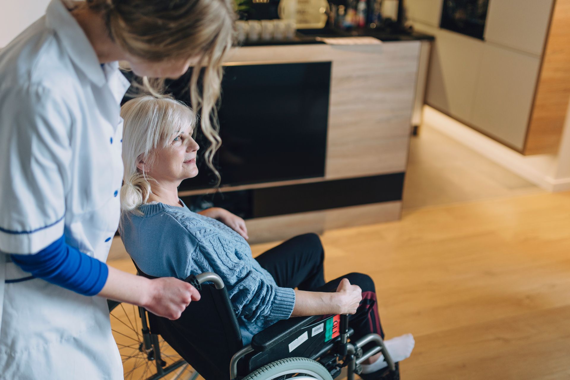 A nurse is helping an elderly woman in a wheelchair.