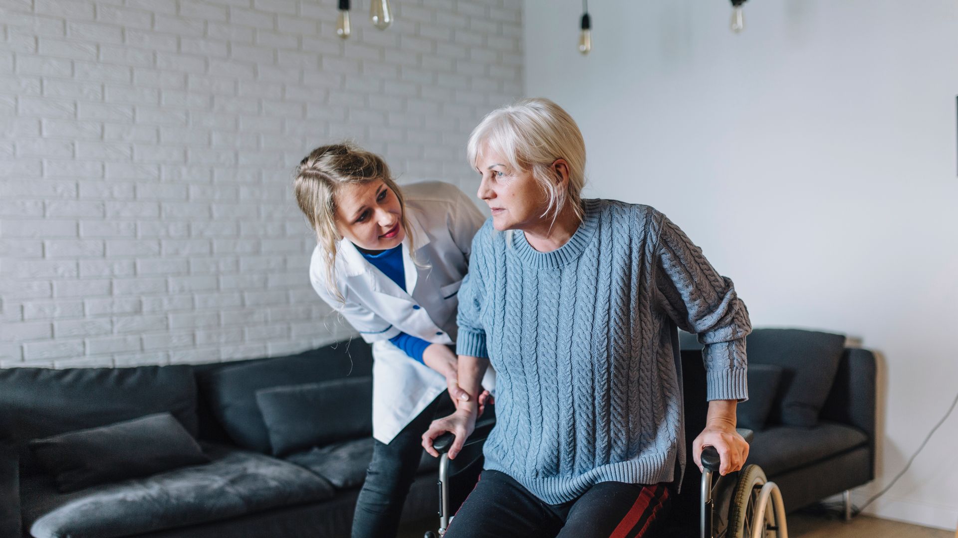 A nurse is helping an elderly woman in a wheelchair.