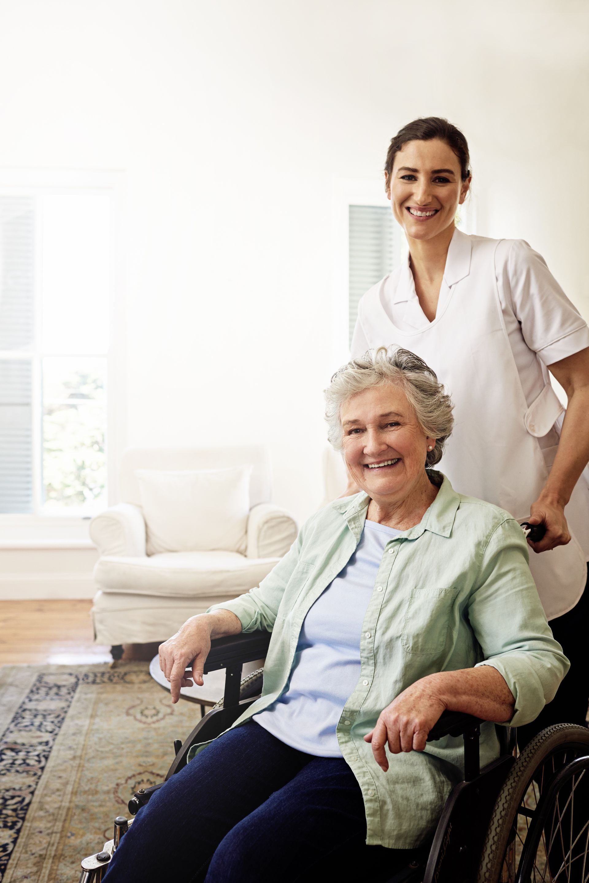 A nurse is standing next to an elderly woman in a wheelchair.