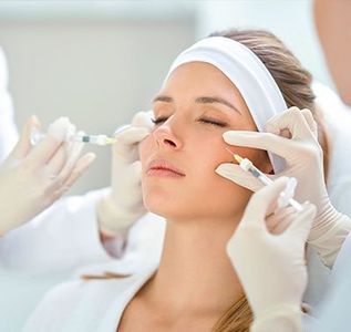 Cosmetician applying facial treatment with gloved hands to a woman in a spa setting