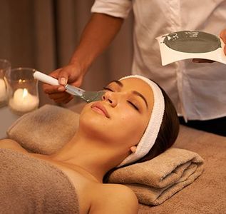 Facial spa treatment with cream being applied to a relaxed client in a warm, candlelit room