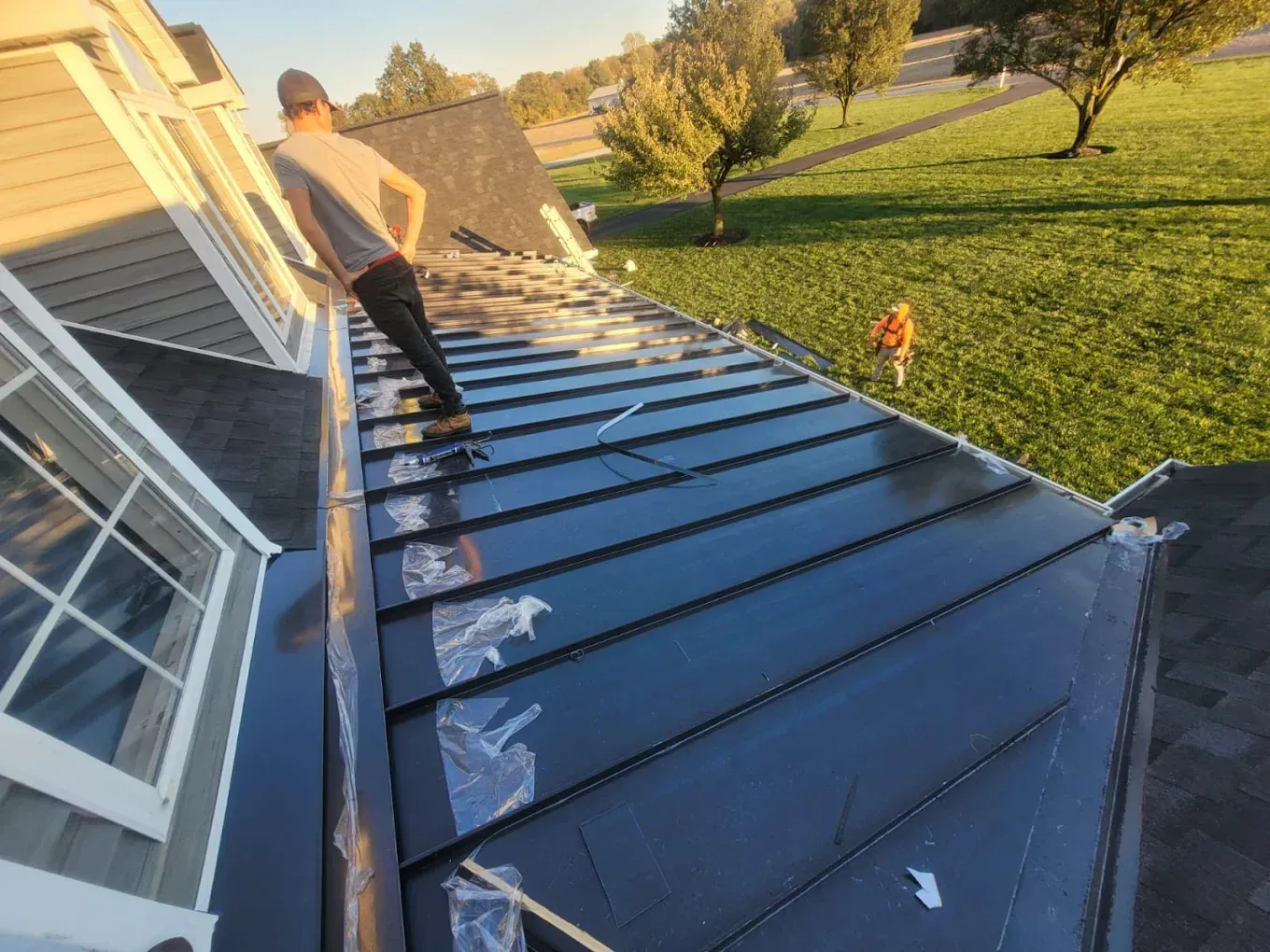Roofer installing metal roofing panels on a residential home in Havre de Grace, MD