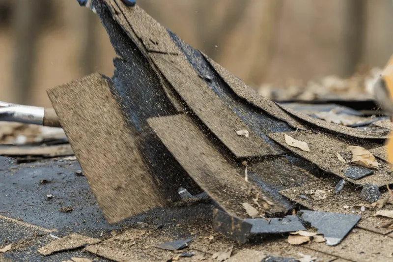 Close-up of old asphalt shingles being torn off during a roof replacement