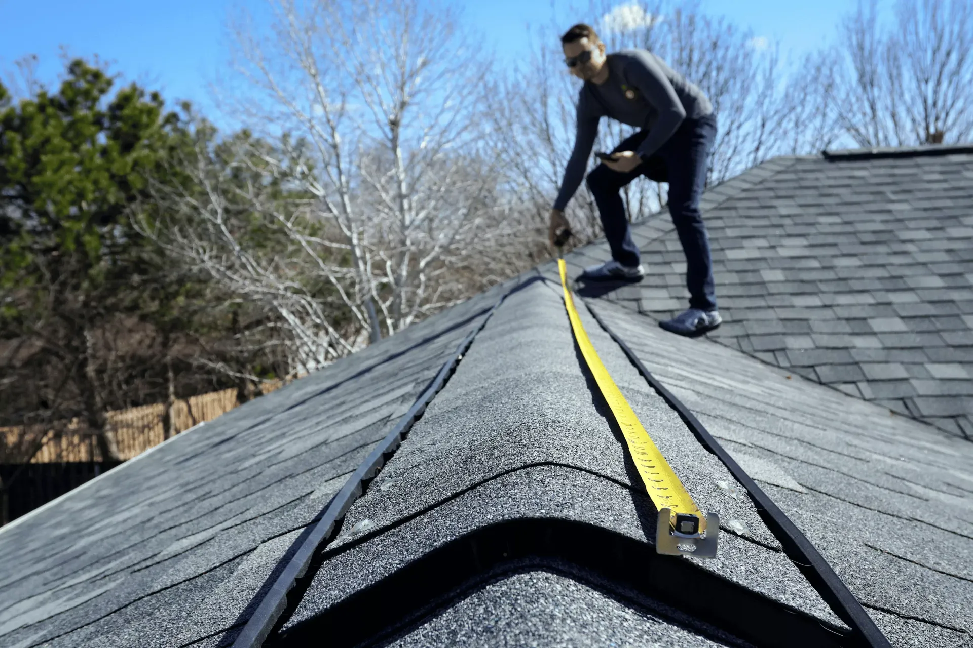 Roofer inspecting storm damage on an asphalt shingle roof in Havre de Grace, MD