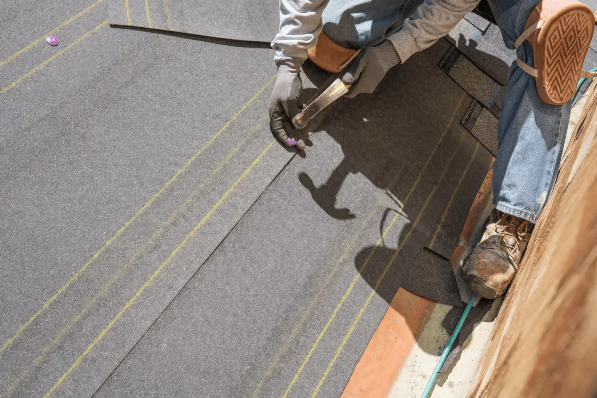 Roofer fastening underlayment to a roof deck during installation in Havre de Grace, MD