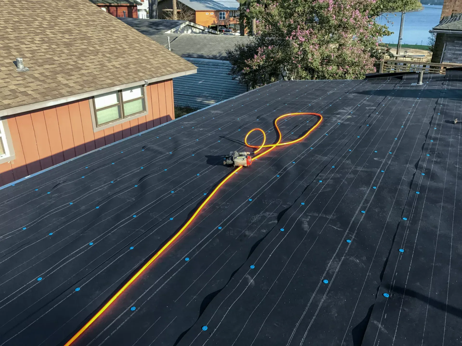 Roofer fastening underlayment to a roof deck during installation in Havre de Grace, MD