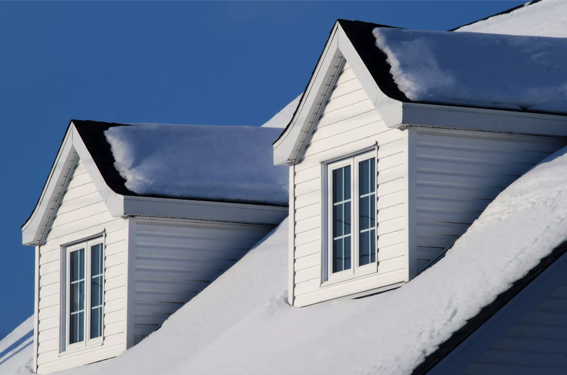 Snow-covered residential roof in Maryland after a winter storm showing potential ice dam risk