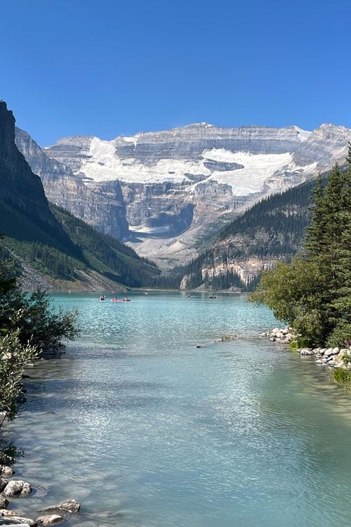 Turquoise lake with mountains and snow under a blue sky.