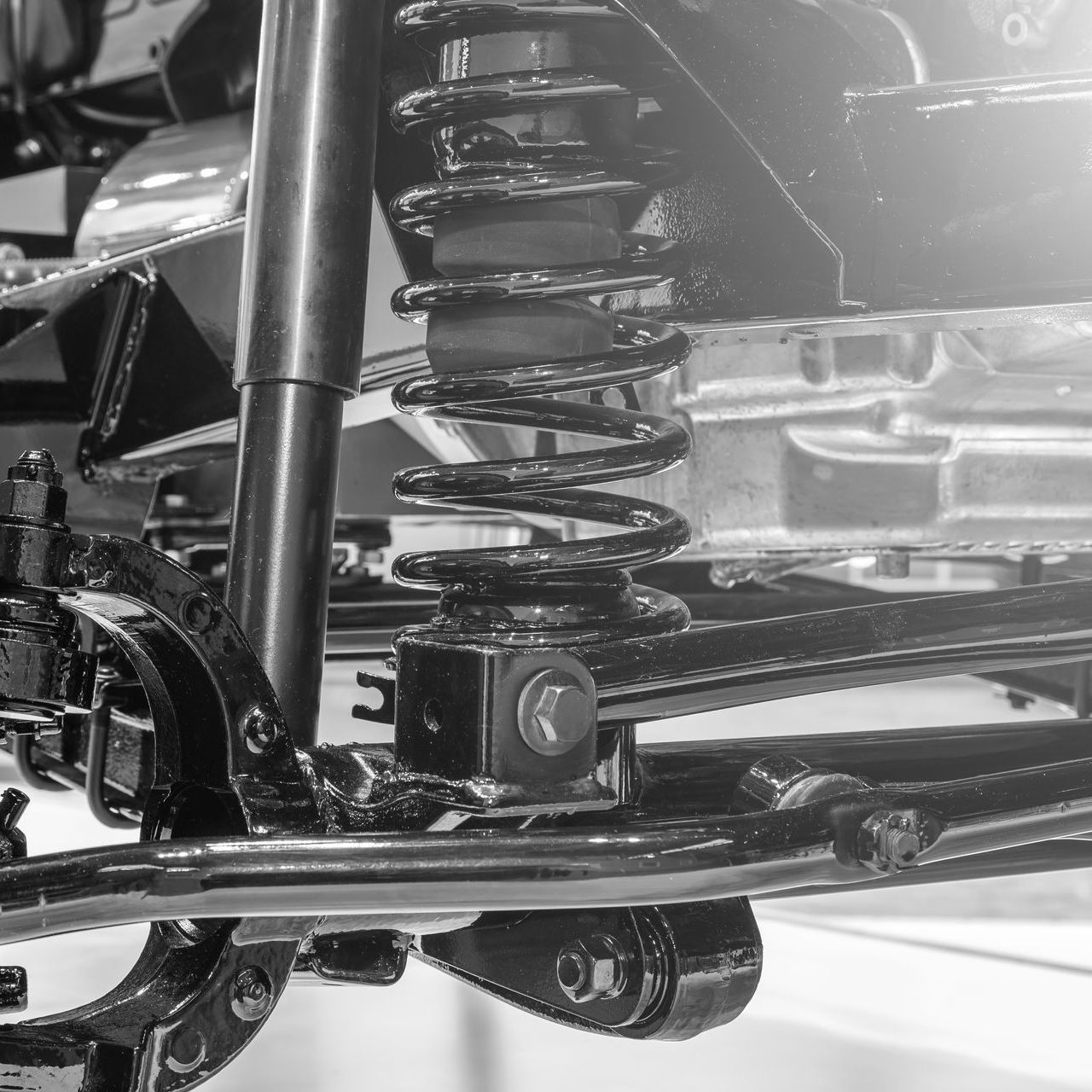 Black-and-white close-up of a vehicle suspension spring and shock absorber assembly