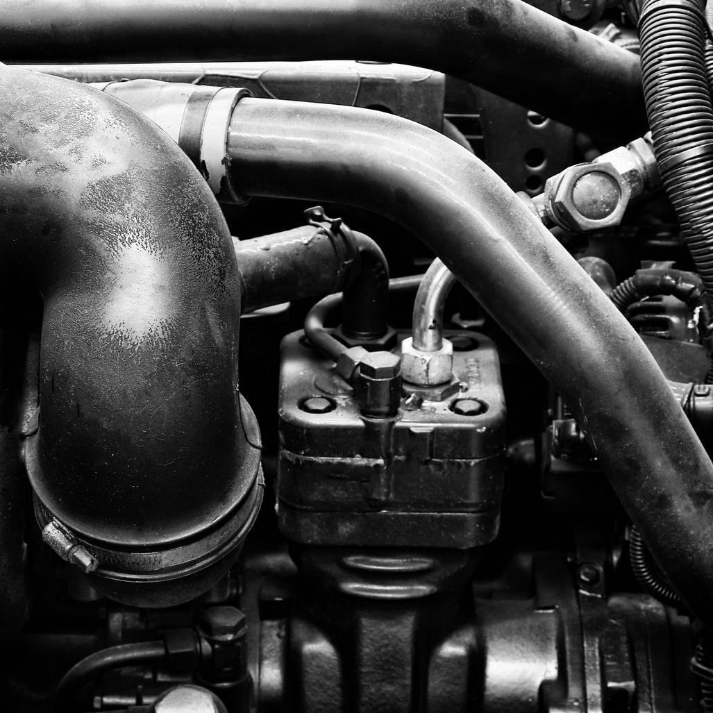 Close-up of a car engine with hoses, pipes, and metal components.