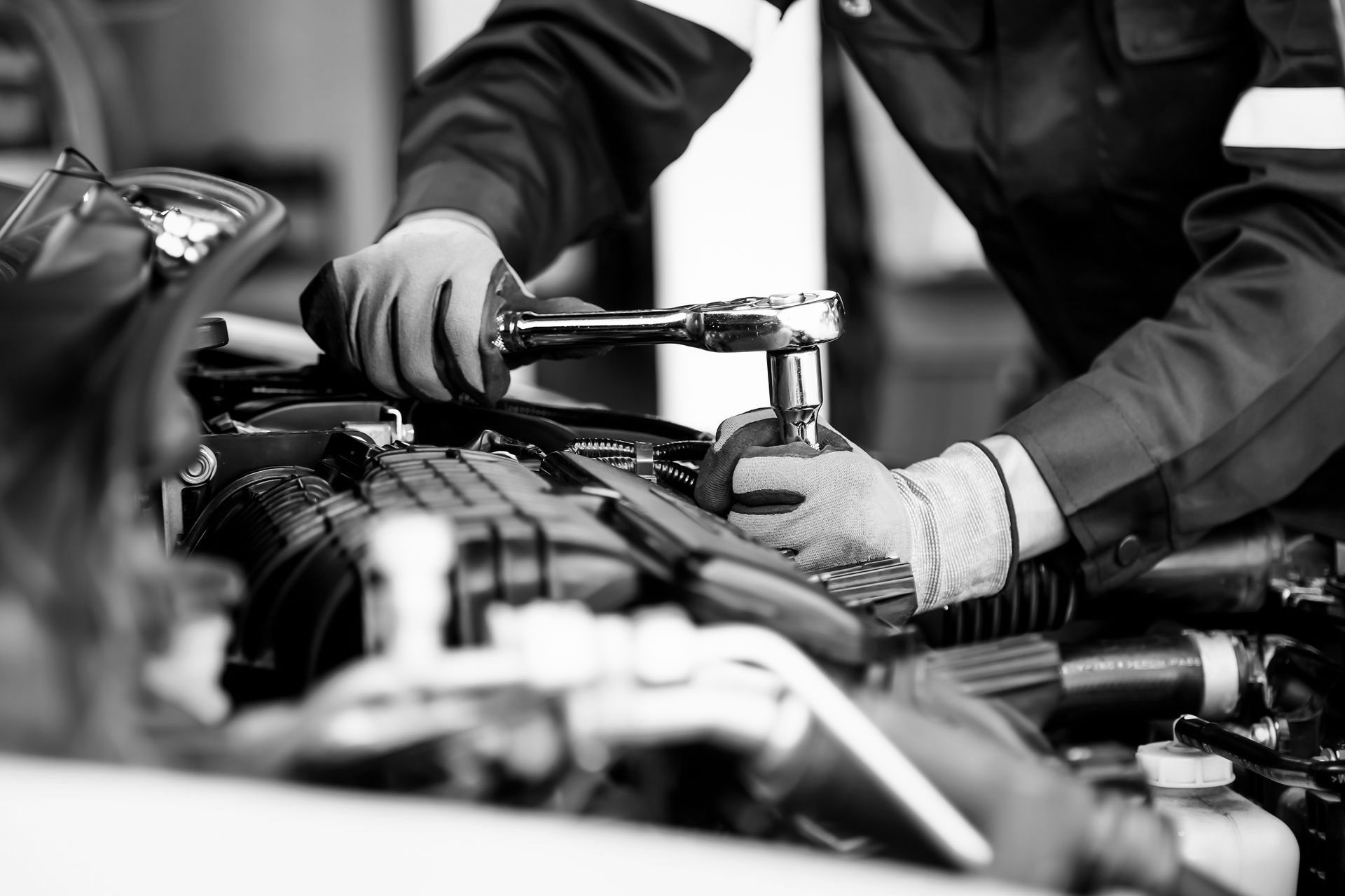 Mechanic repairing a car engine with a wrench in a garage
