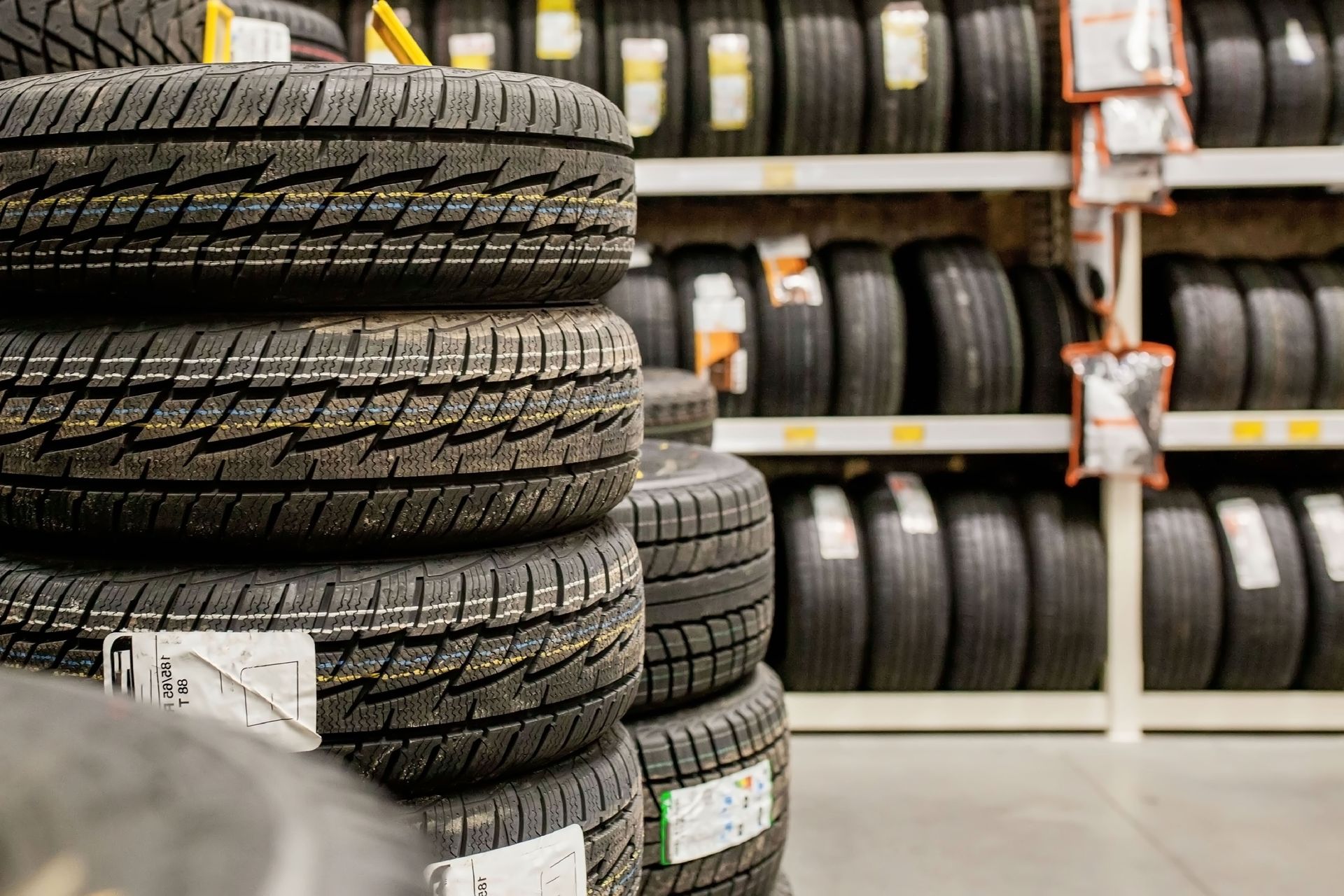 Stacks of black tires on display in a store aisle with shelves in the background