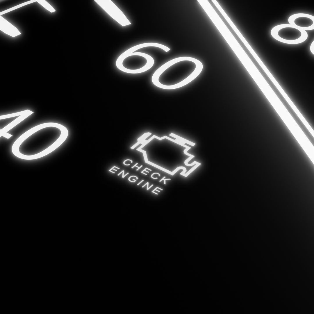 Glowing dashboard check engine light between speedometer numbers 40, 60, and 80