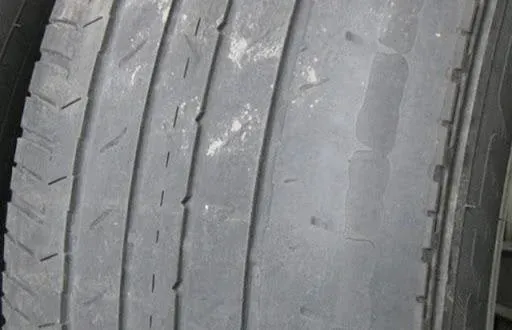 Close-up of a worn tire with minimal tread remaining; the surface is gray and weathered.