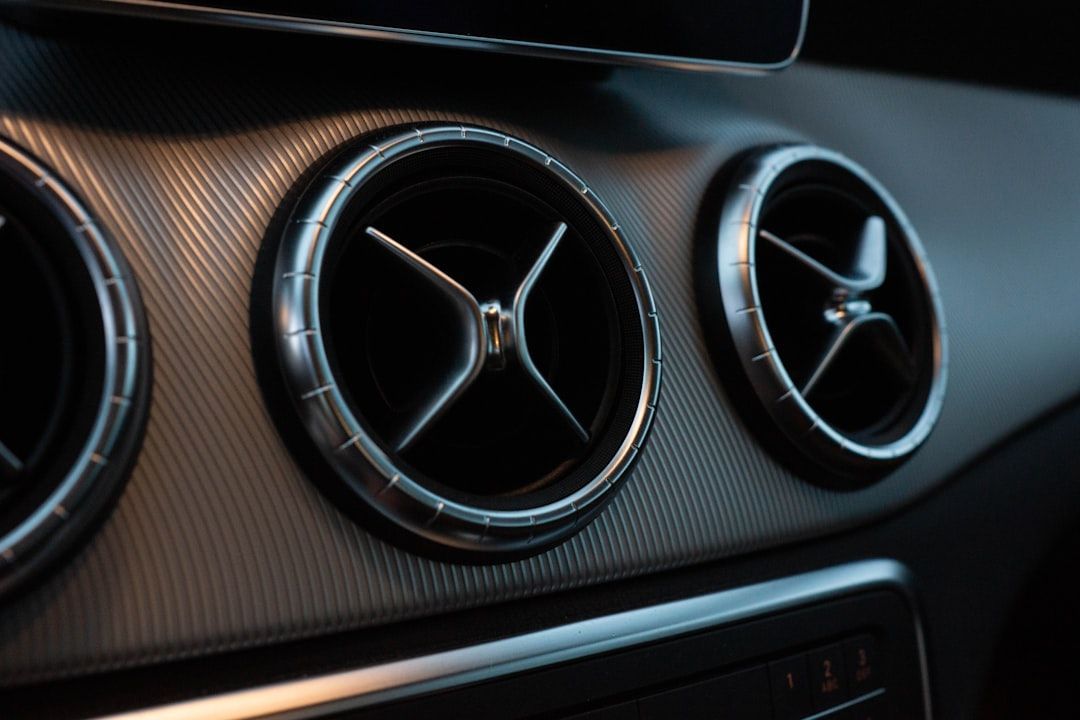 Car dashboard with three circular air vents on a carbon-fiber-style panel