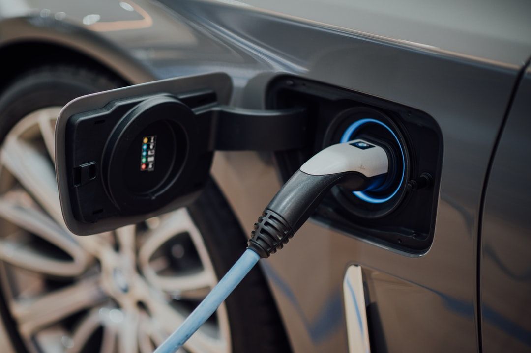 Electric car charging port with cable plugged into a dark gray vehicle