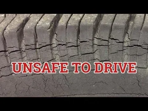 Close-up of a cracked, worn tire with the text 