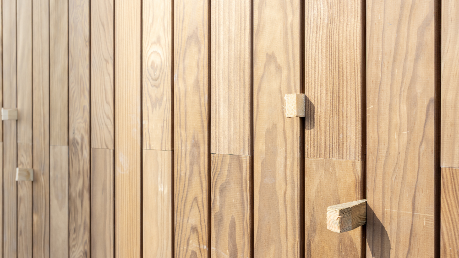 Vertical wooden slats with two small geometric wooden handles, in warm light.