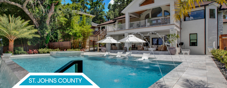 A luxury home in St. Johns County with a pool, umbrellas, and lush landscaping.