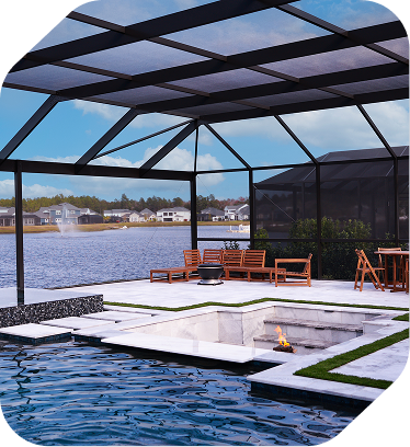 Sunken fire pit next to a pool under a black screen enclosure, overlooking a lake with a fountain in the distance.