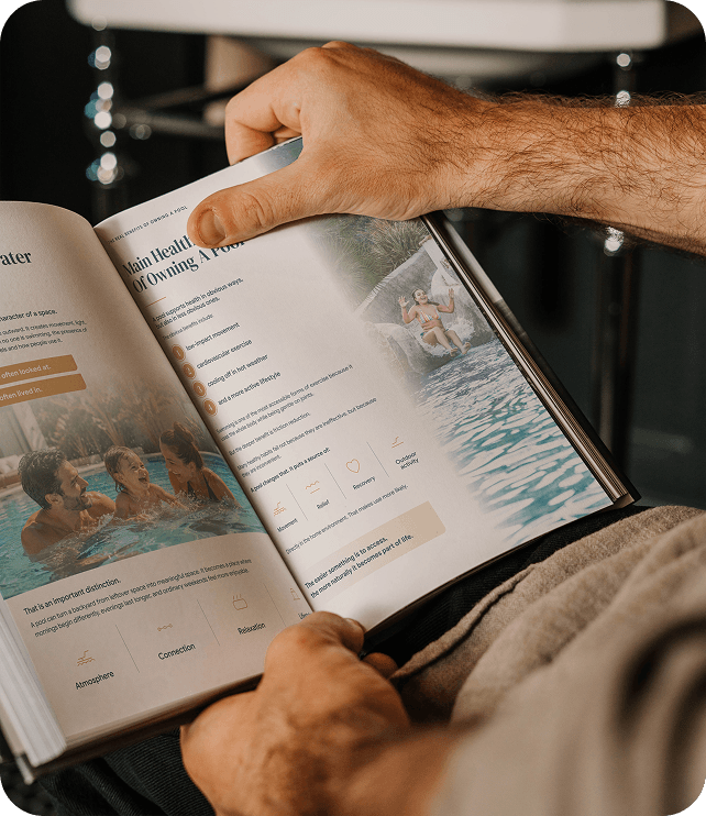 Hand turning pages of a travel magazine on a couch, showing photos and text.