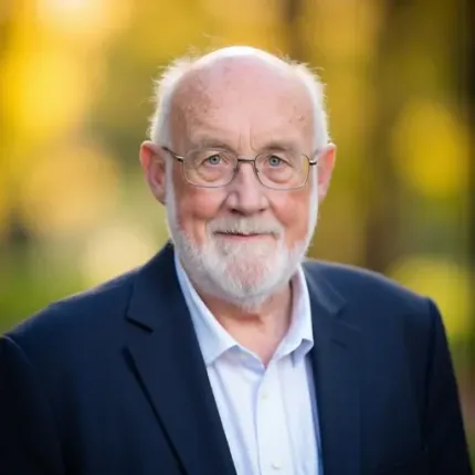 A man with glasses is holding a glass of liquid in his hand