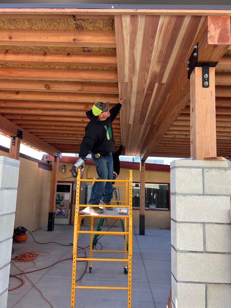 A man on a ladder working on a wooden structure