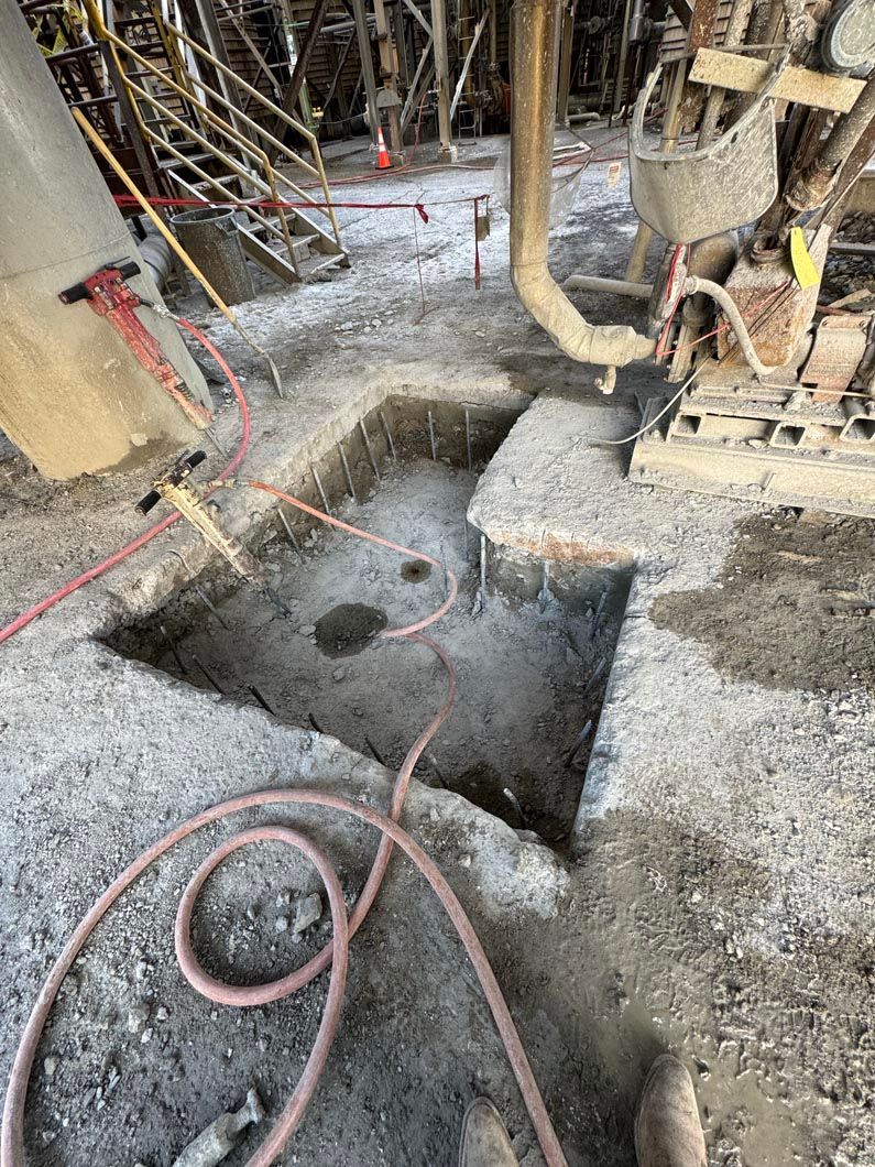 A hose is laying on the ground next to a hole in the ground.