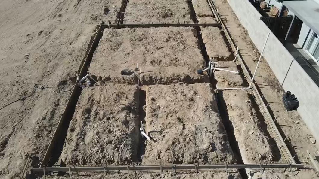 A concrete slab is being built in a dirt field.