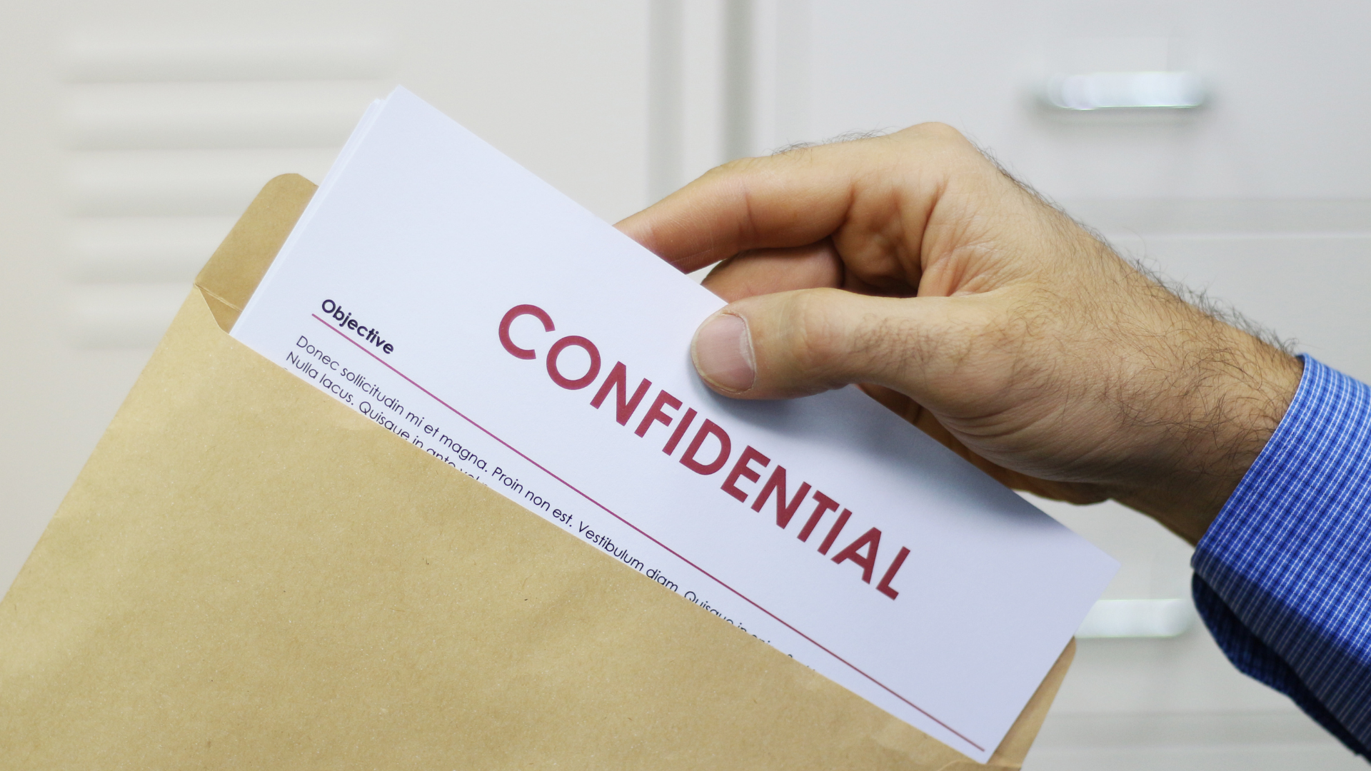 A person is holding a confidential document in an envelope.