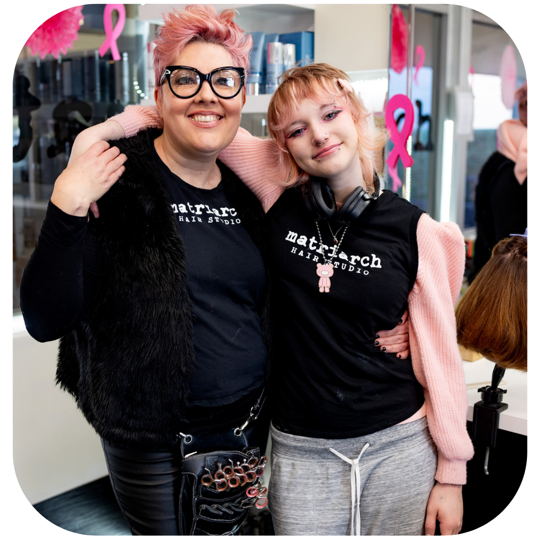 2 people wearing a t-shirt uniform are standing with arms around each other.
