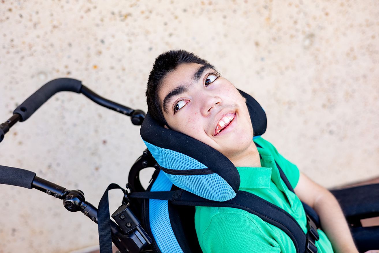 Boy in a green shirt, sitting in a wheelchair.