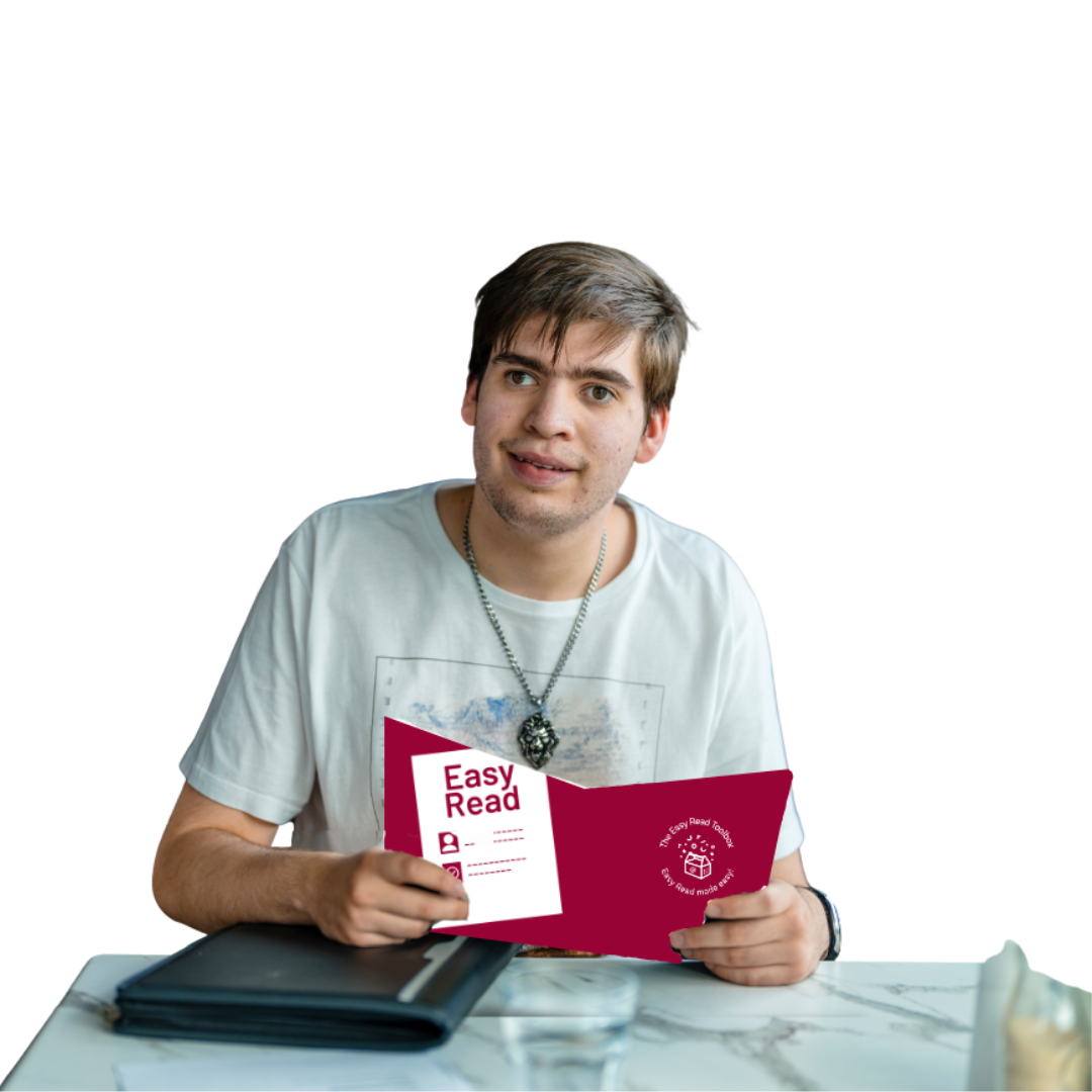 Image of an individual sitting at a table holding an Easy Read book.
