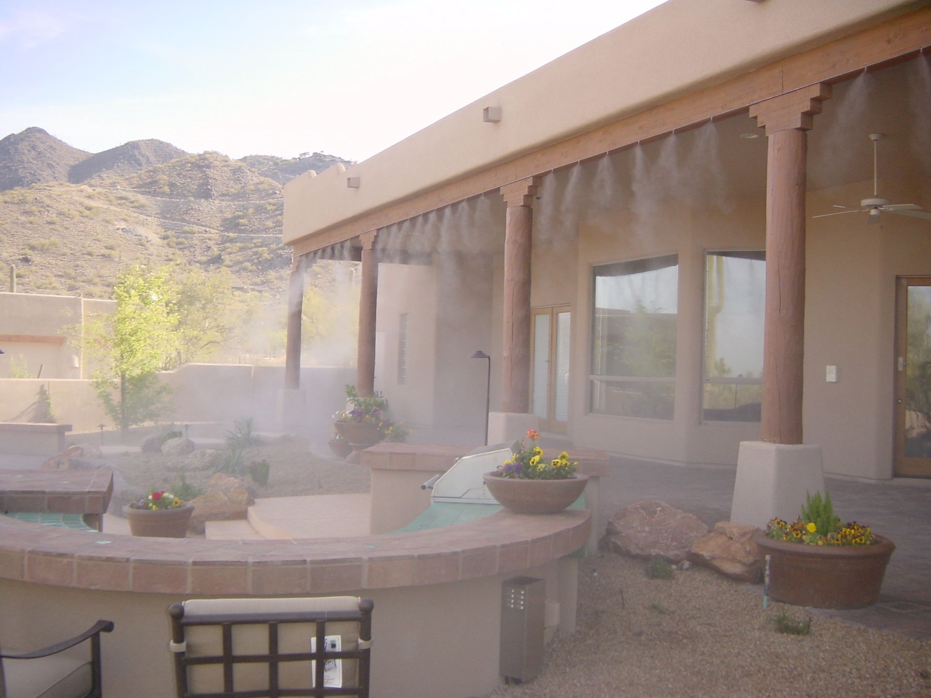Desert patio with potted plants, stucco columns, and mountain backdrop in soft light