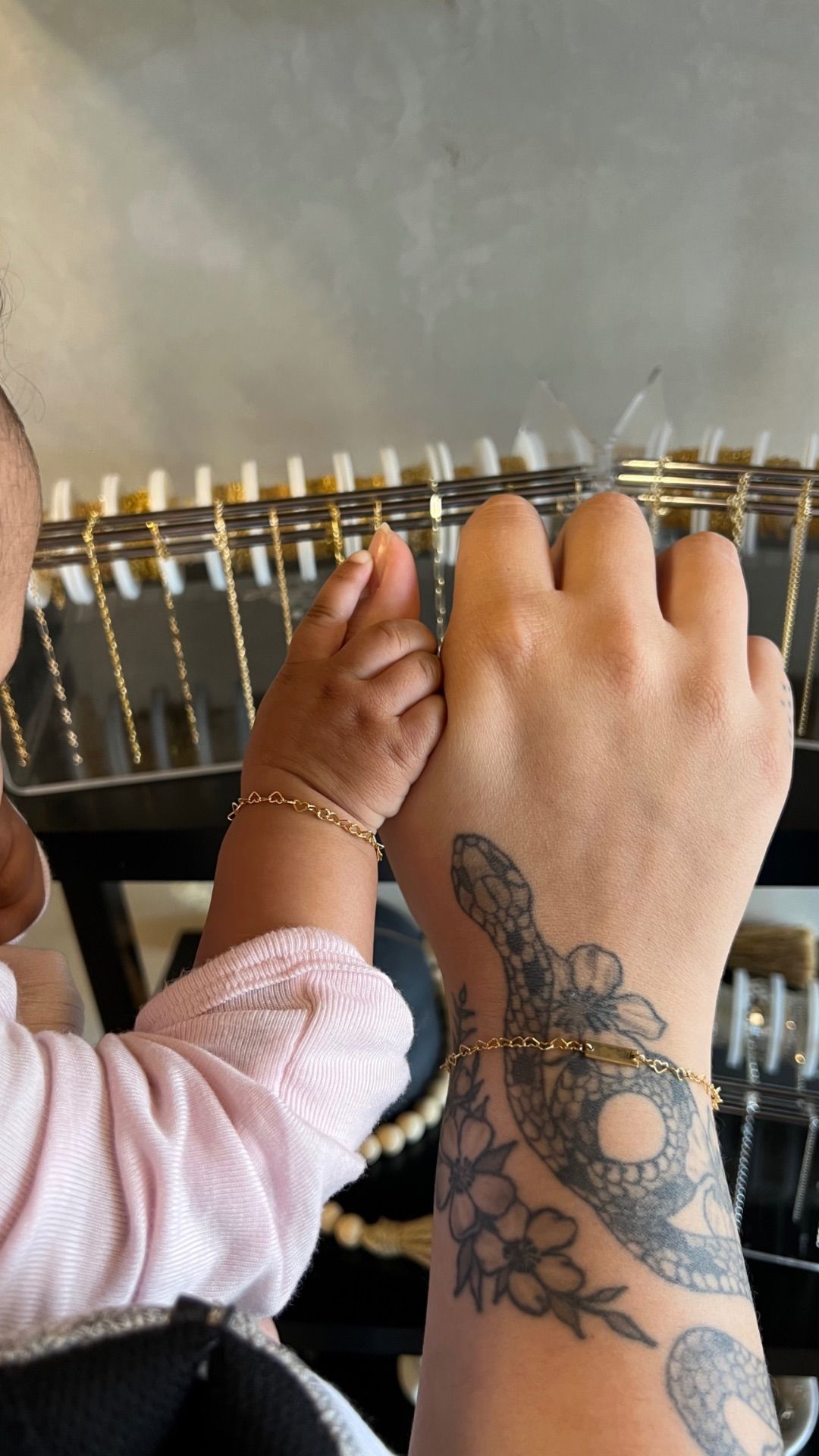 Hand and tattooed arm reaching into a row of hanging hangers, selecting clothing.