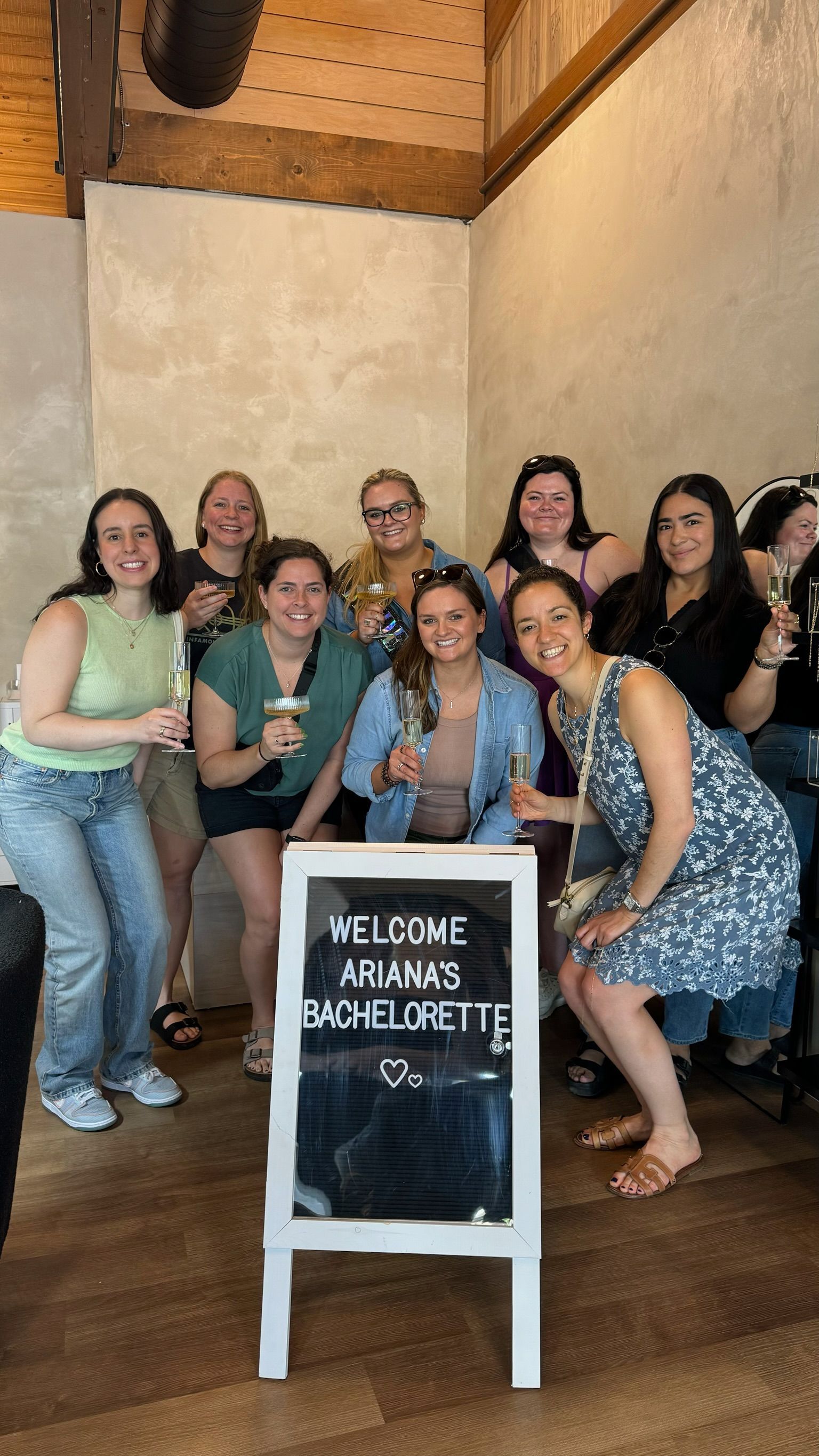 Group of women posing indoors around a chalkboard sign reading “Welcome Amanda Michelle”