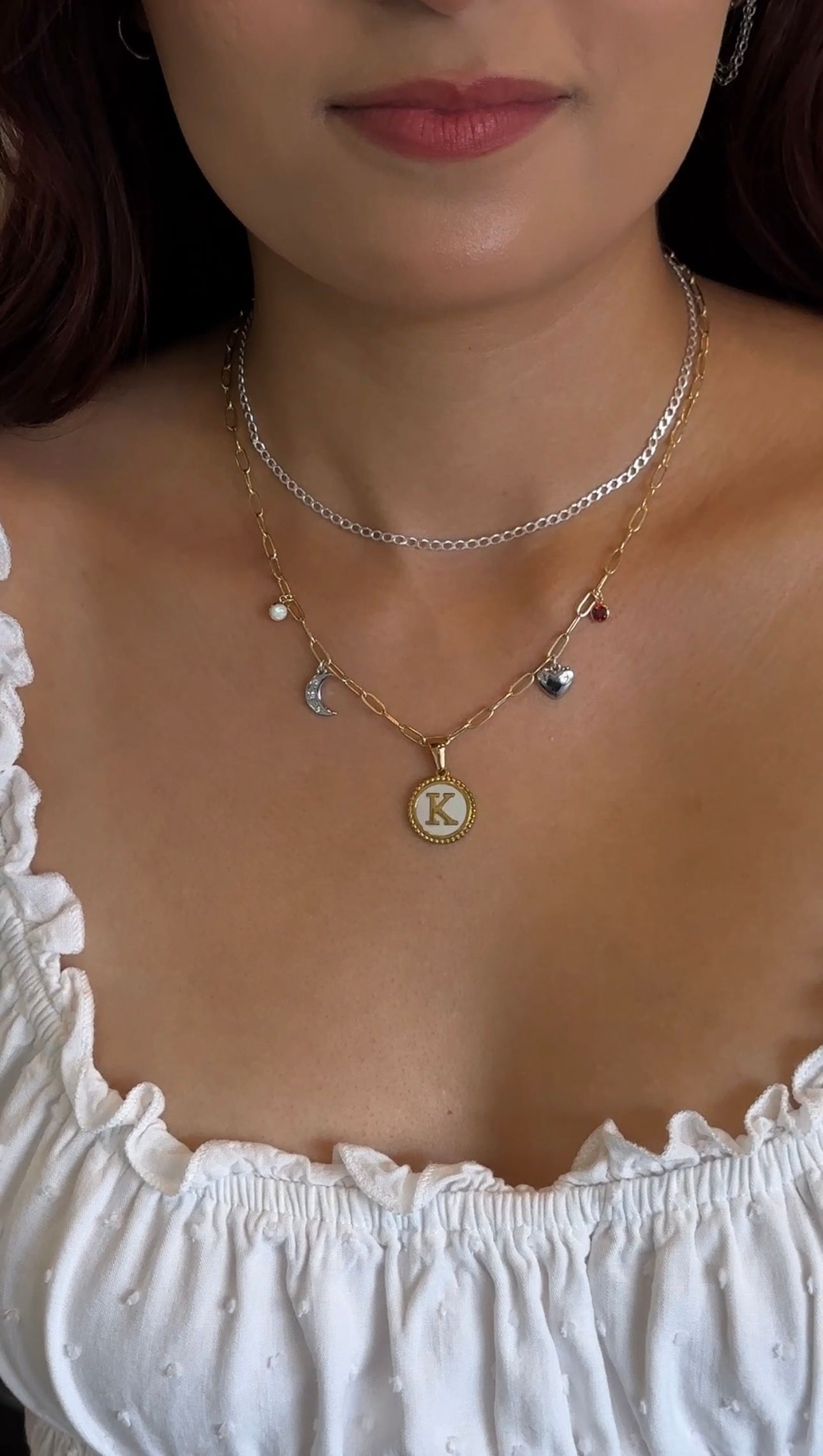 Woman wearing layered silver necklaces and a white off-shoulder blouse, close-up on neckline