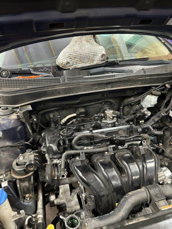 Blue car engine bay with components exposed, being worked on.