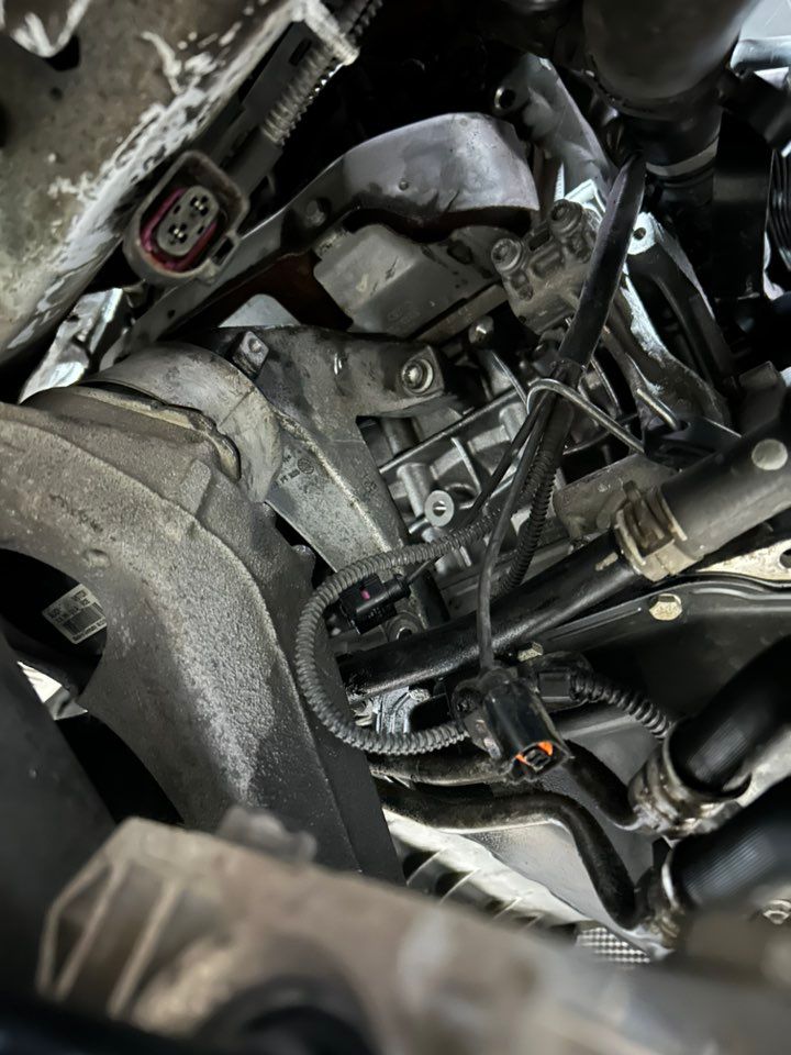 Car engine compartment with various components, wires, and hoses visible.